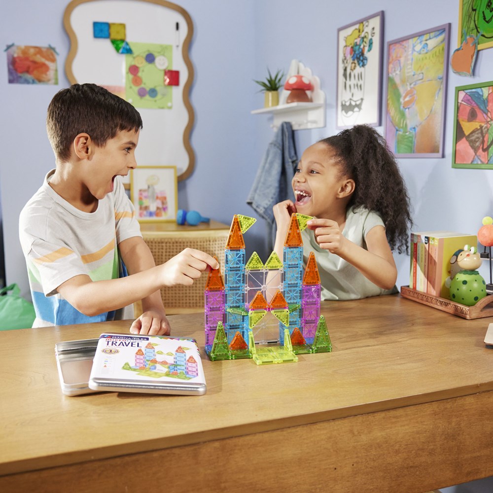 Two children playing with colorful magnetic building blocks at a table in a classroom setting