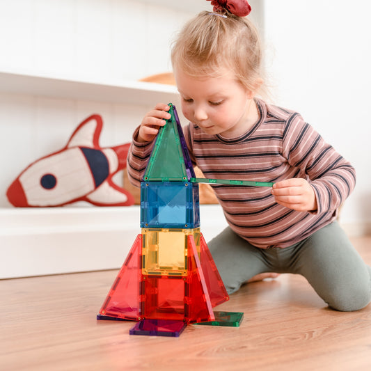 Child building a colorful magnetic tile tower with Connetix magnetic tiles