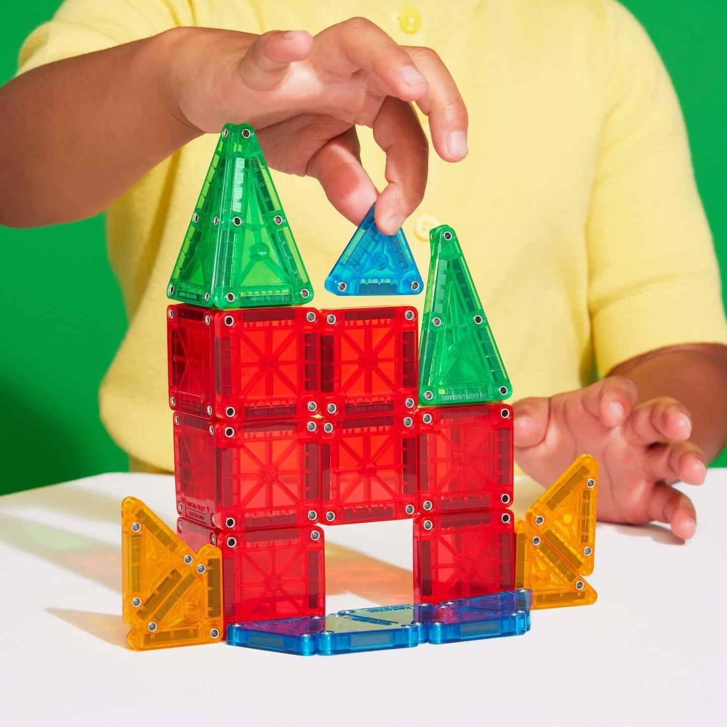 Child building a colorful castle with magnetic blocks on a white surface