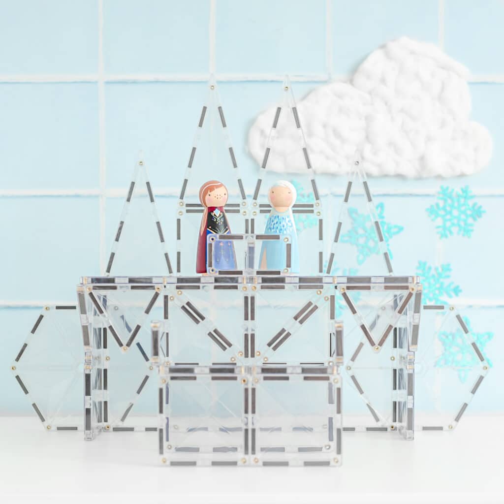 Model of a building with two figures on top against a light blue tiled wall with cloud and snowflake decorations