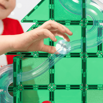 Child placing accessories on a magnetic tile Christmas tree during creative play