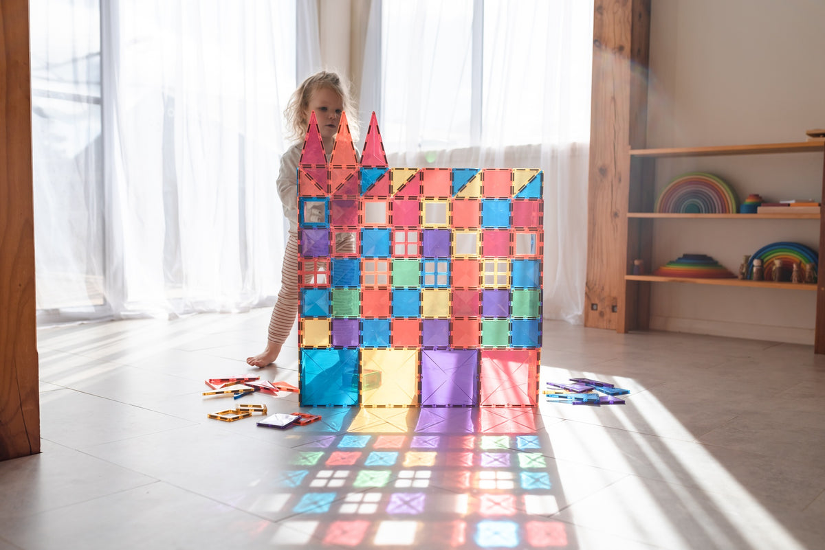 Child building a colorful magnetic tile tower with Connetix magnetic tiles