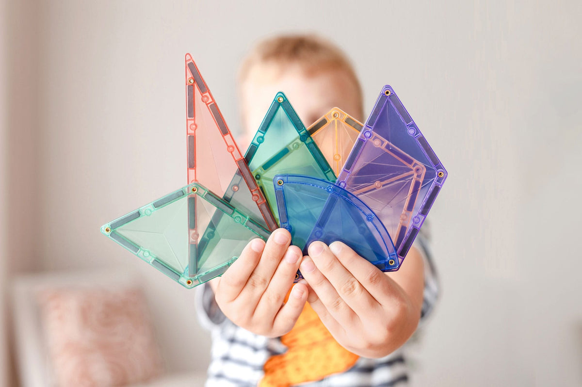 Child holding colorful transparent geometric shapes 