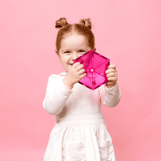 Child holding a pink cube-shaped 