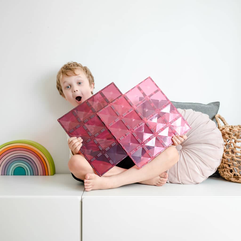 Child holding pink geometric cushions 