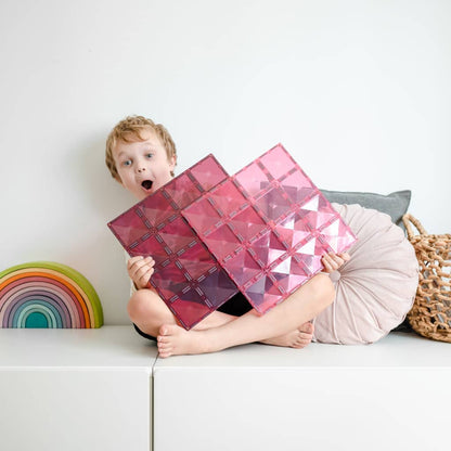 Child holding pink geometric cushions 