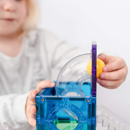 Child playing with a blue and clear toy structure, possibly a marble run