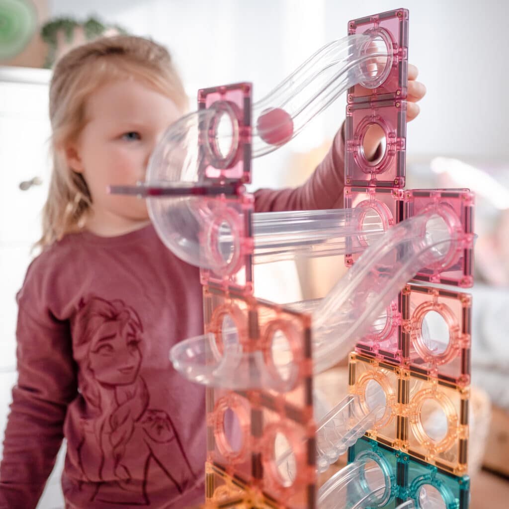 Child playing with a transparent and pink geometric toy structure