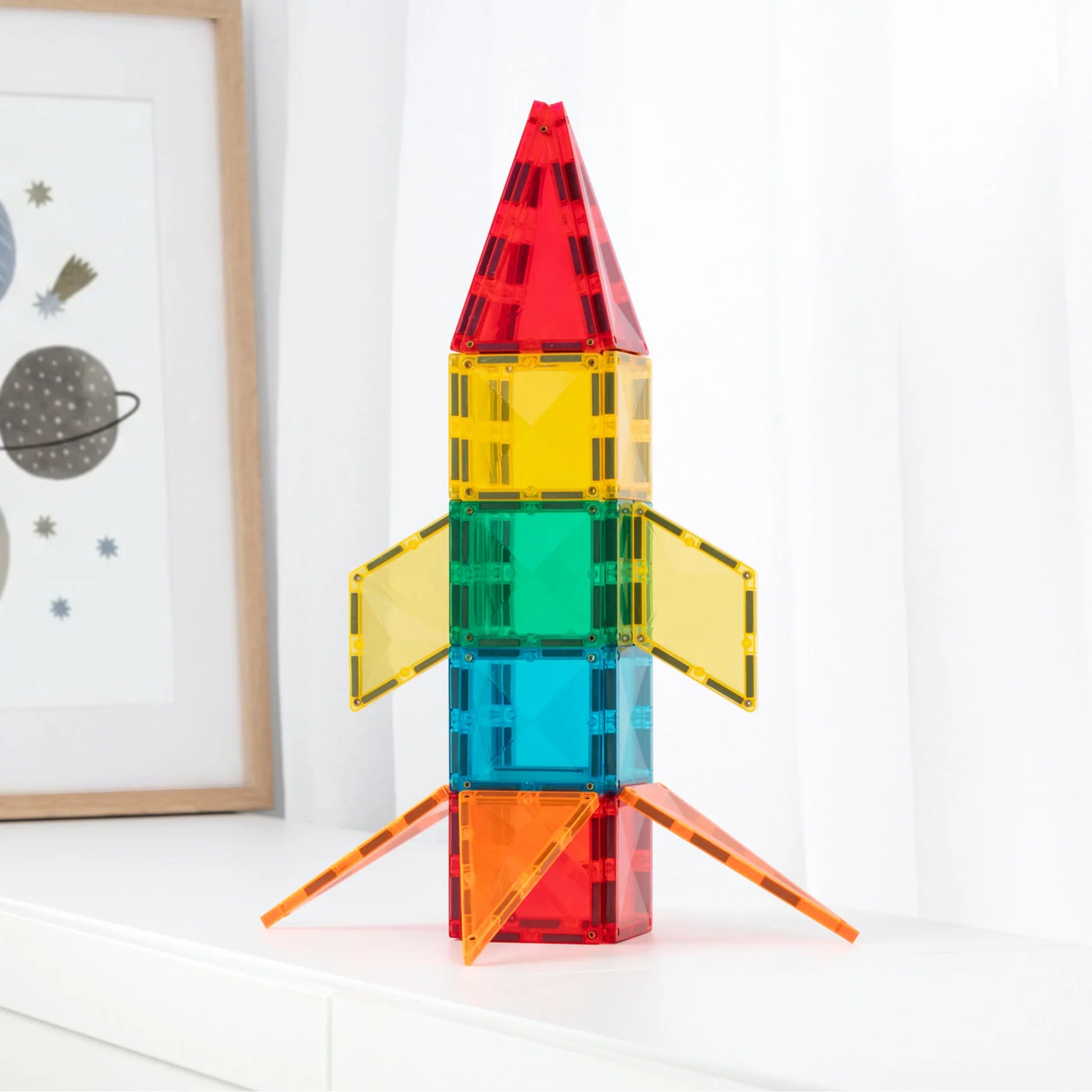 A colorful toy rocket built from translucent magnetic building blocks, standing 