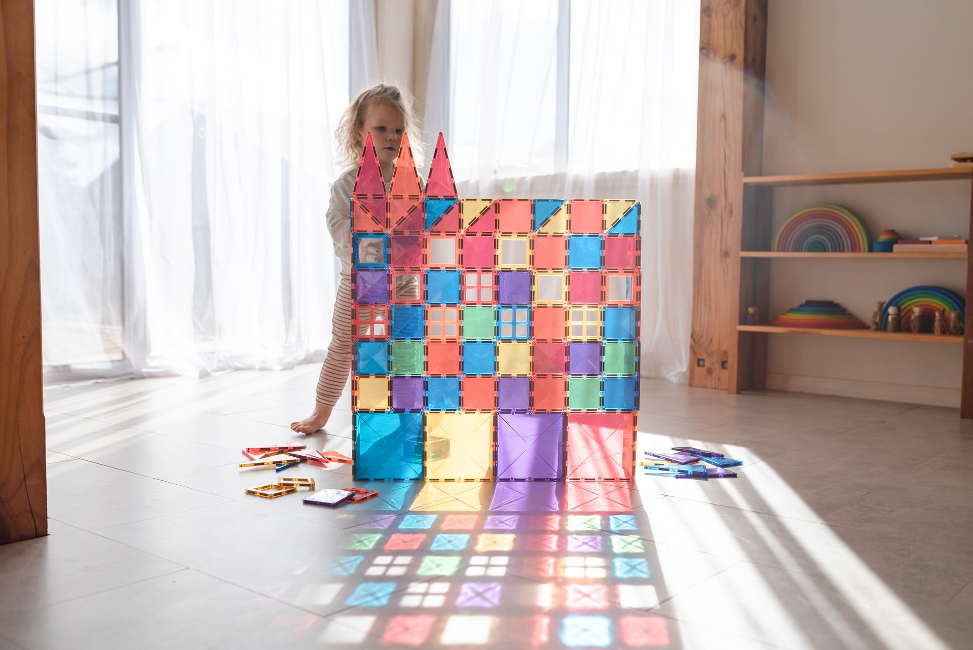 Child building a colorful magnetic tile tower with Connetix magnetic tiles