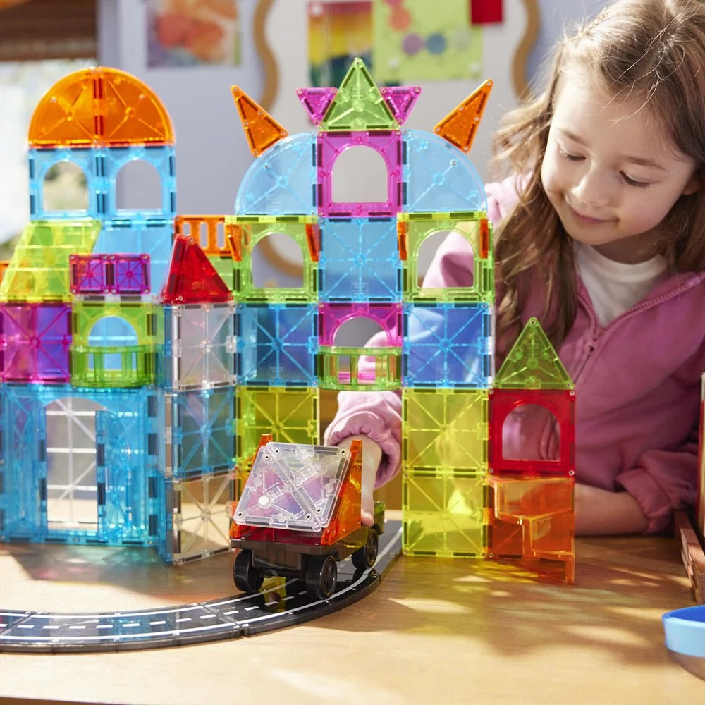 Child playing with colorful magnetic building blocks and a train set 