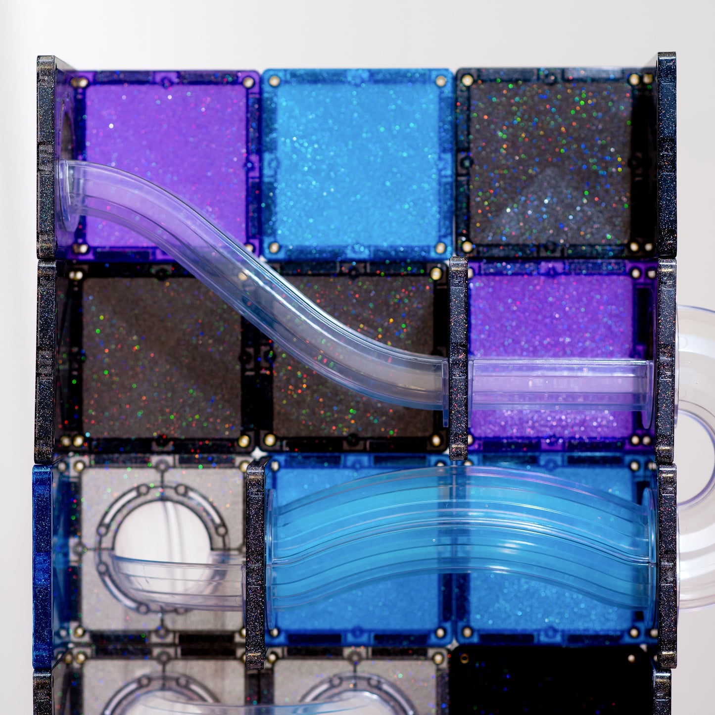 A close-up of a transparent block puzzle or magnetic tile assembly with curved clear plastic channels