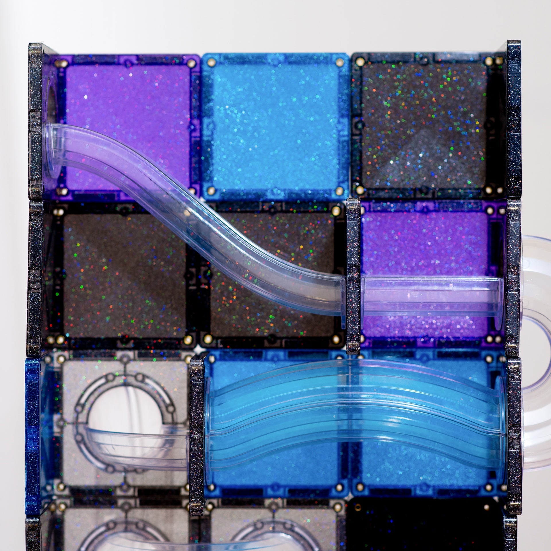 A close-up of a transparent block puzzle or magnetic tile assembly with curved clear plastic channels