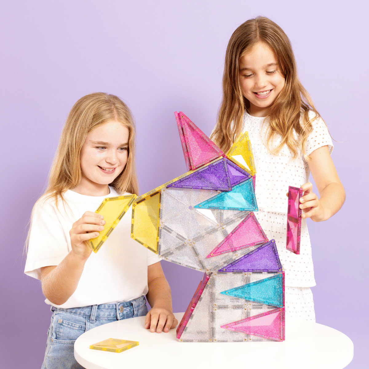 Two children playing with colorful geometric building blocks 