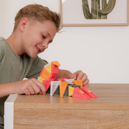 A young boy with blond hair smiling while playing with colorful geometric toy blocks